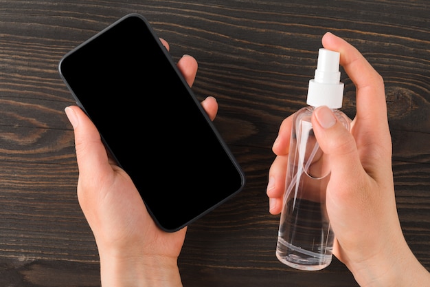 Hands spraying sanitizer on a phone