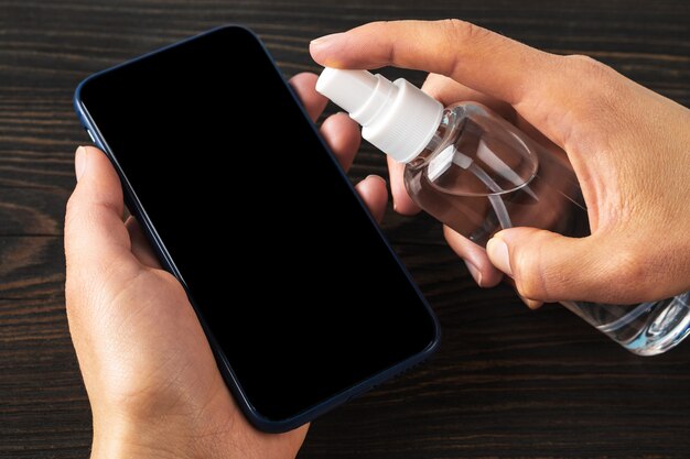 Hands spraying sanitizer on a phone