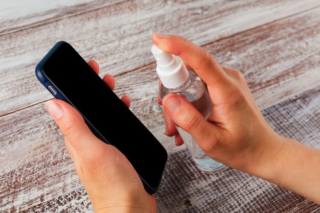 Foto mani che spruzzano disinfettante su un telefono