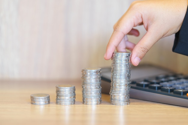 Hands stacking money for growing chart of coins with calculator