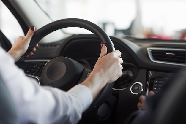 hands on steering wheel woman in official clothes trying her new car in automobile salon