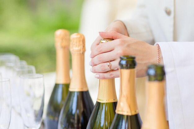 Hands of the steward opening bottles of champagne at the wedding ceremony