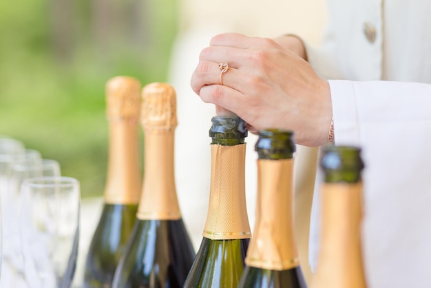 Руки стюарда открывают бутылки шампанского на свадебной церемонии