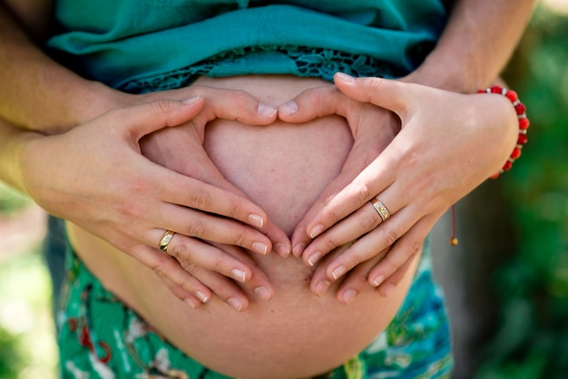 Hands on the stomach of a pregnant girl.