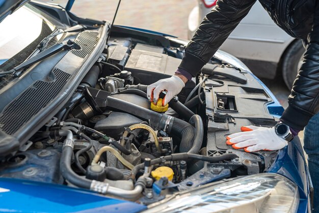 Le mani di un uomo forte in guanti ispezionano l'auto sotto il cofano per danni concetto di riparazione auto concetto di ispezione auto