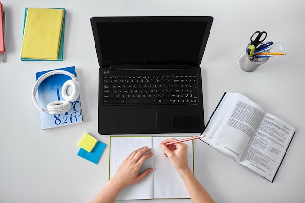 hands of student with notebook and laptop on table