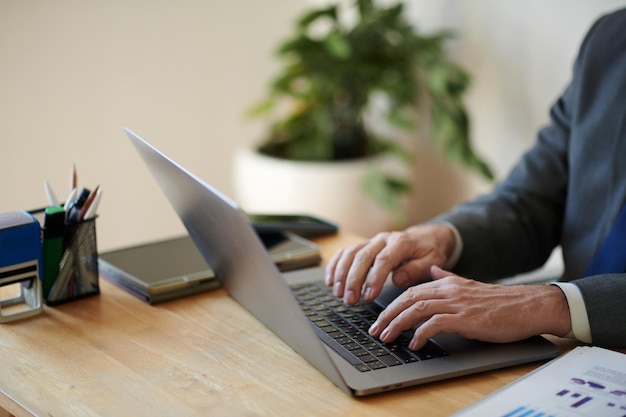 Hands of successful entrepreneur working on laptop at desk in his office