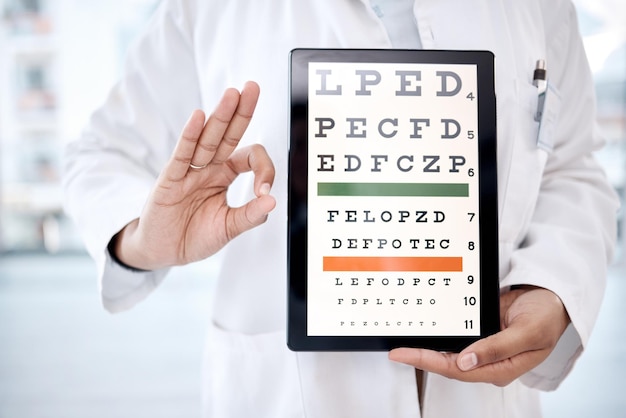 Photo hands tablet screen and snellen chart in hospital for vision examination in clinic healthcare ok gesture or woman ophthalmologist or medical doctor holding technology showing letters for eye test