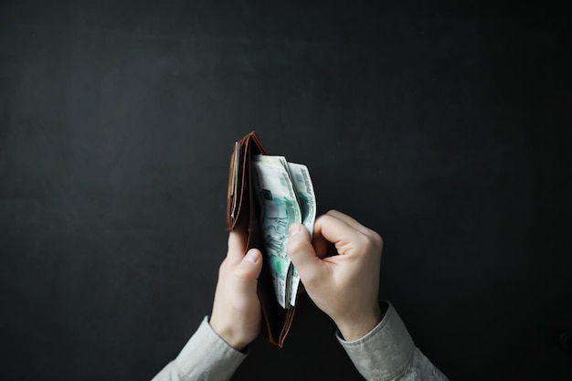 Hands take out cash banknotes from a wallet on a gray background Foreign currency