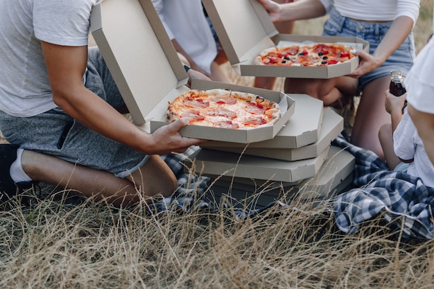 Hands take out pizza from boxes at picnic