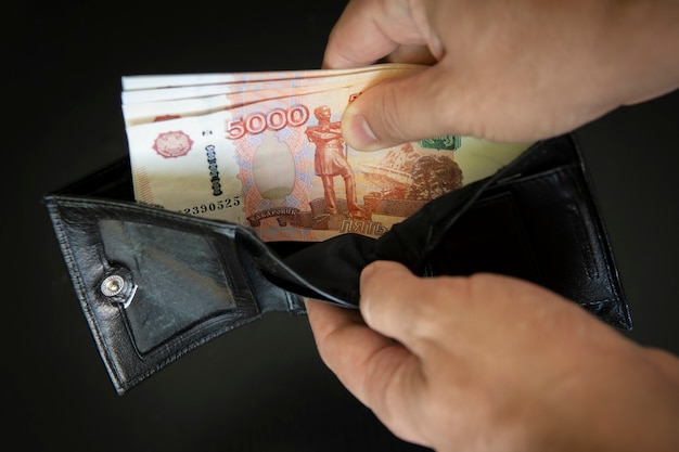 Hands take out russian rubles from wallet. Closeup on a man's hands as he is getting a banknote out of his wallet. a lot of money. a rich man