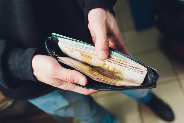 Photo hands take out russian rubles from wallet closeup on a man's hands as he is getting a banknote out of his wallet