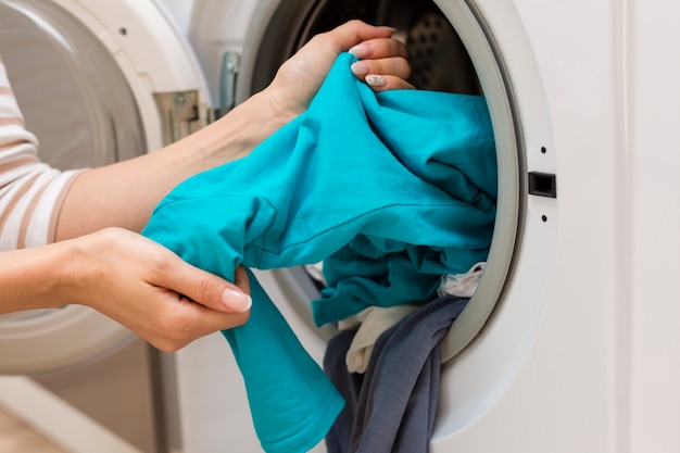 Photo hands taking clothes out washing machine