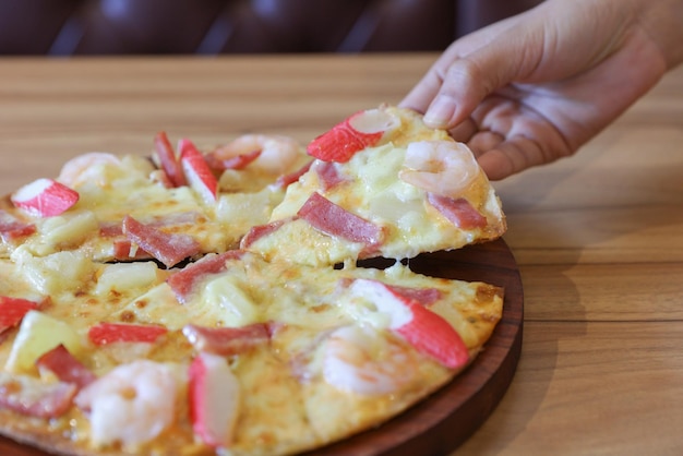 Hands Taking Slices Of Pizza on wooden board