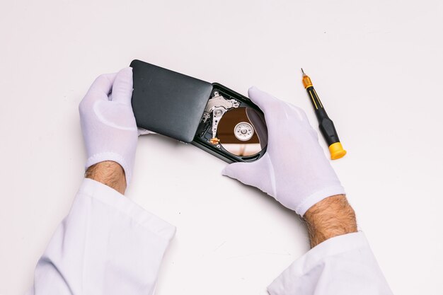 Hands of a technician with gloves repairing a hard drive