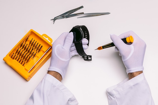 Hands of a technician with gloves repairing a wristwatch smartwatch