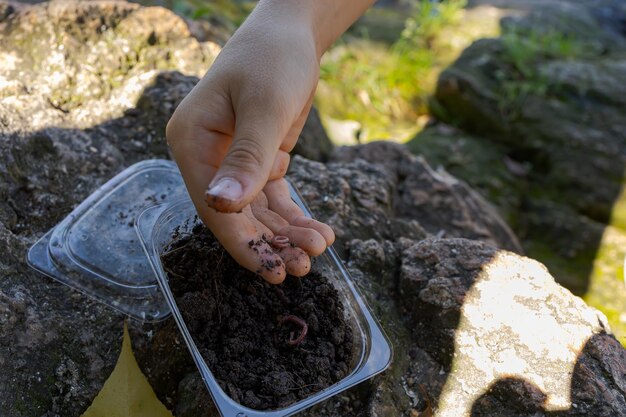 Foto le mani di un adolescente che prende l'esca con i vermi con le dita pesca sportiva sul fiume in estate