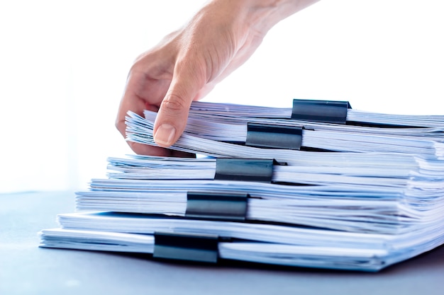 Hands touching office paper. Stacks documents files with black clip. 