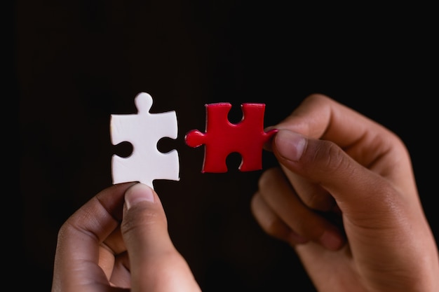 Hands trying to fit two puzzle pieces together