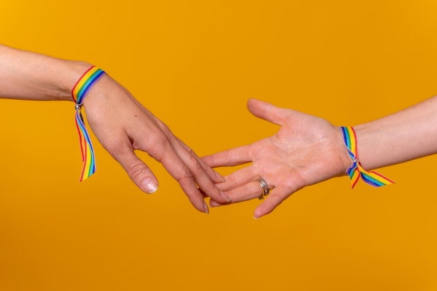 Hands of two women caressing and touching fingers LGBT concept on a yellow background couple of lesbian girls