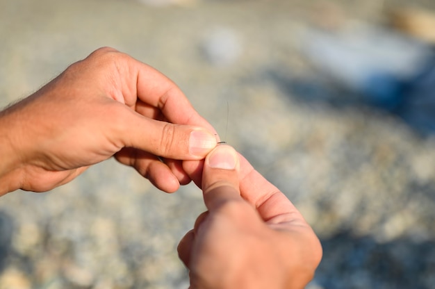 Hands tying a fishing line on a fishing hook