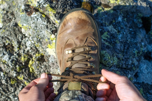 Hands tying shoelaces on a worn hiking boot close-up