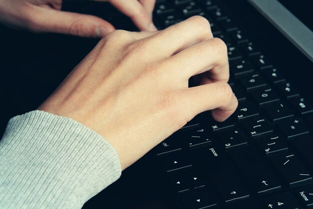 Hands typing on laptop keyboard toned vintage style