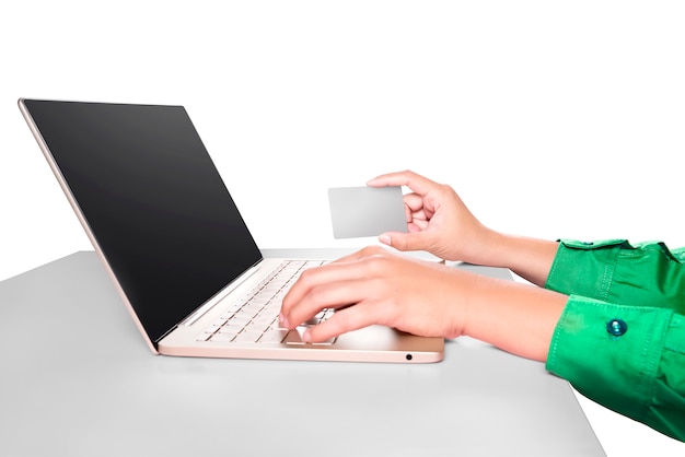 Hands typing on laptop while holding credit card on desk