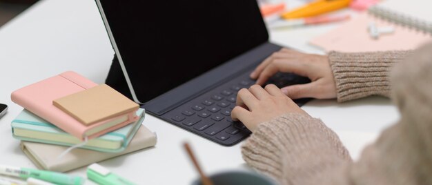 Hands typing on tablet keyboard at working desk