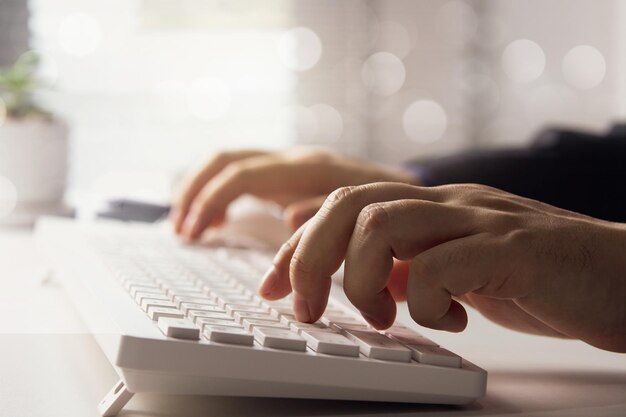 Hands typing on a white keyboard focusing on the users work