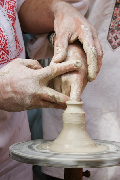 점토 워크숍 동안 우크라이나 세라믹 마스터와 그의 제자의 손. 점토 제품을 만드는 손의 근접 촬영 샷