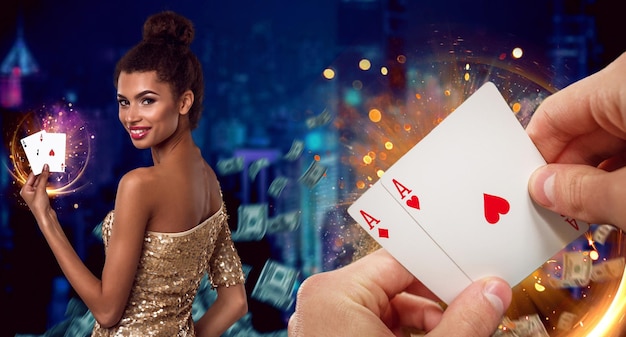 Hands of unknown guy holding two aces. Smiling mulatto woman showing playing cards while posing against colorful background with flying dollars and sparkling golden lights. Poker, casino. Close-up