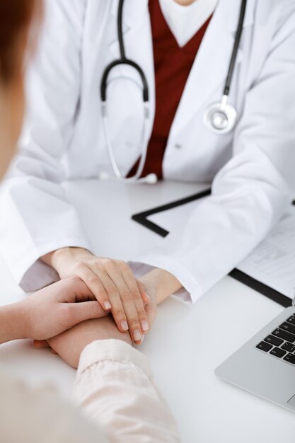 Hands of unknown woman-doctor reassuring her female patient, close-up. Medicine concept.