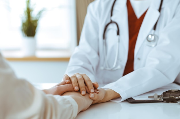 Hands of unknown woman-doctor reassuring her female patient, close-up. Medicine concept.