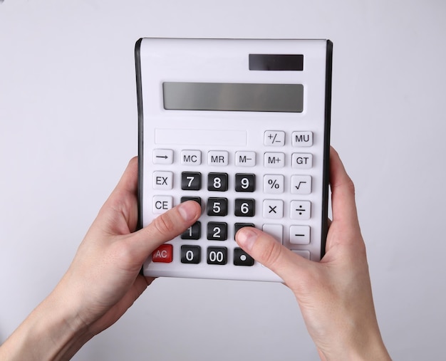 Hands using calculator on gray background