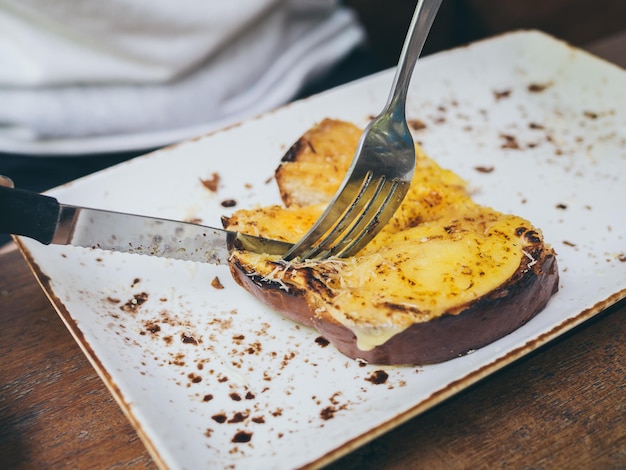 Hands using knife and fork to cut cheese toast