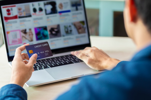 Руки, используя ноутбук и кредитную карту для онлайн-платежей