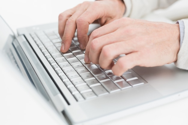 Hands using laptop on white surface