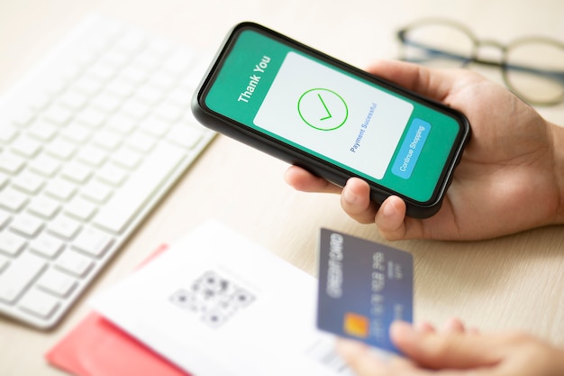 Hands using a phone and credit card for online payment