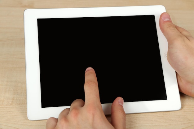 Hands using tablet PC on wooden table background