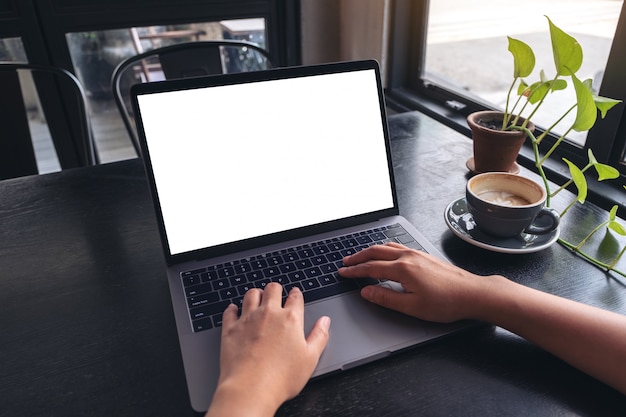 Hands using and typing on laptop with blank white desktop screen