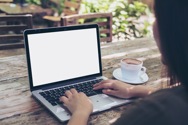 Photo hands using and typing on laptop with blank white screen on vintage wooden table