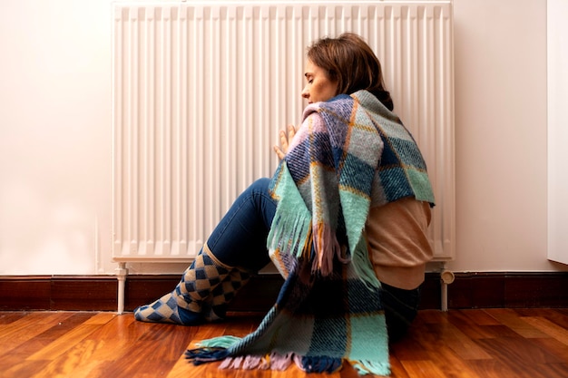 Photo hands of a very cold woman covered with a blanket due to a problem with the radiators or lack of heating heating maintenance