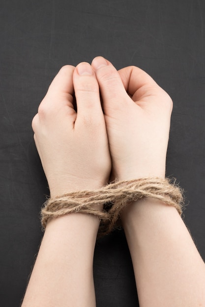 Photo hands of a victim woman tied up with rope