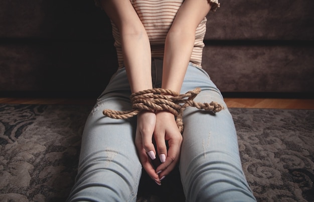 Photo hands of a victim woman tied with rope.