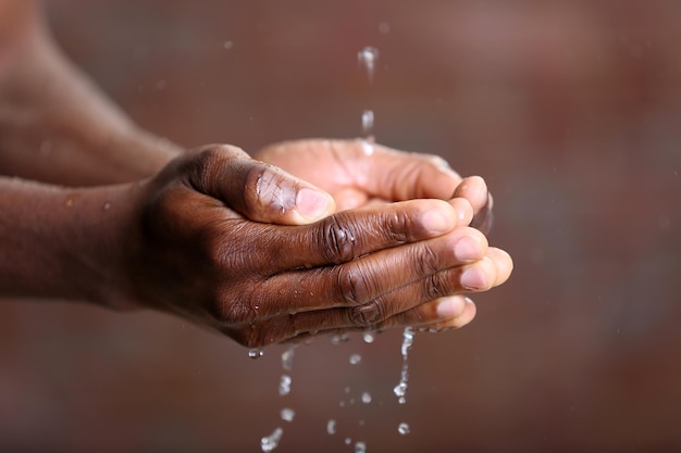 手洗いコンセプト レンガ壁の背景に男の手に注ぐ水