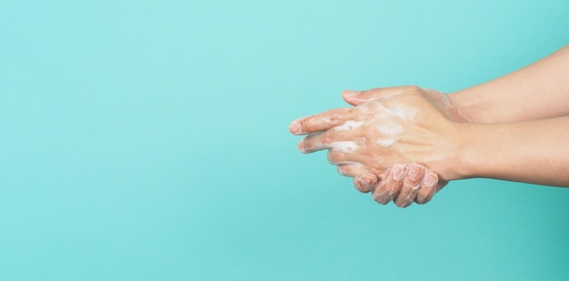 Hands washing gesture with foaming hand soap on green and Tiffany Blue background