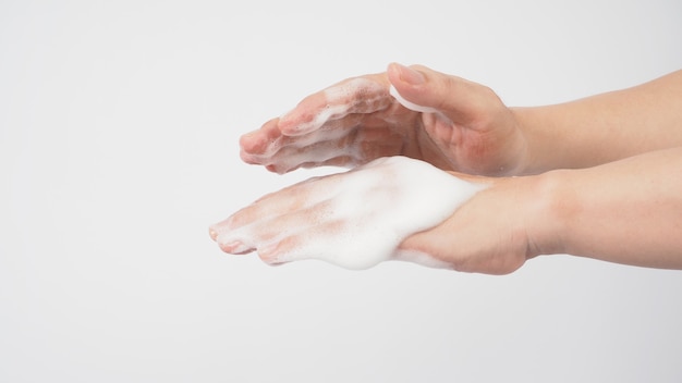 Hands washing gesture with foaming hand soap on white background.