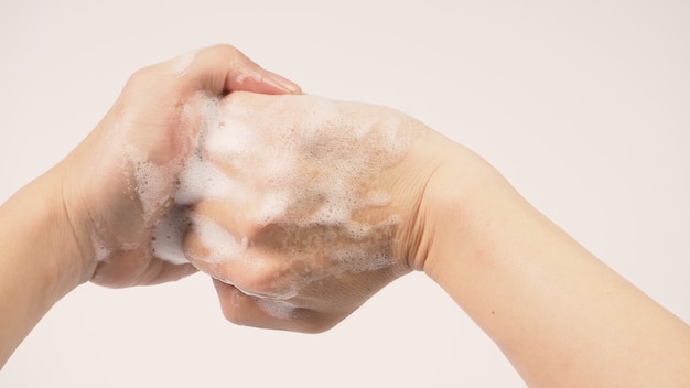 白い背景の上の泡立つハンドソープでジェスチャーを洗う手。
