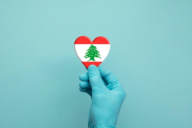 Mani che indossano guanti chirurgici protettivi che tengono il cuore della bandiera del libano